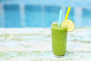 Freshly blended green fruit smoothie in glass with straw photo