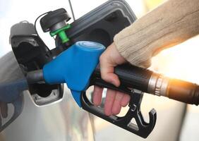 Mans hand refilling the car with a gas pump photo