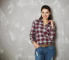 Young woman leaning against a gray wall looking at camera photo