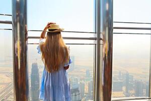 Girl tourist with mobile phone by the window of skyscraper of the Burj Khalifa in Dubai photo