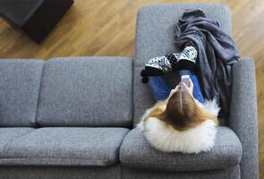 Woman lying on sofa while writing a text message on her cell phone photo
