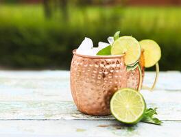 Natural homemade lemonade in cooper mugs on rustic wooden background photo