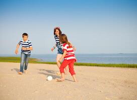Brother and sisters play with a beach ball outdoors photo