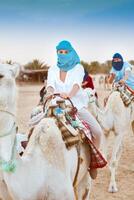 Young caucasian woman tourist riding on camel in Sahara desert photo