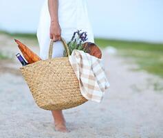 Young woman holding picnic basket with bottle of wine and baguette photo