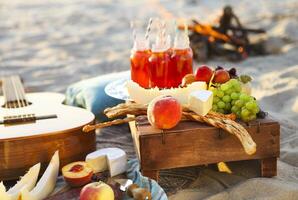 Picnic on the beach at sunset with fruits and juices photo