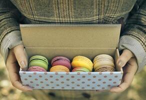 Woman holding box with colorful French macaroons in her hands photo