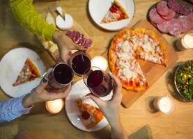 Table with various food served with red wine and candles photo