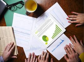 Business team hands at work with financial reports and a tablet computer photo