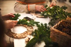 Cropped view of florist hands making Christmas wreath with fir branches photo