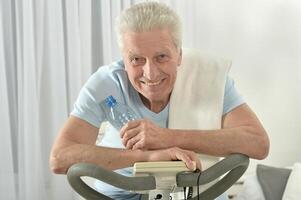 An elderly man is exercising on an exercise bike photo