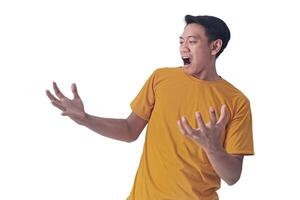 Portrait of an Asian man wearing a orange T-shirt, expressing surprise and shock with open palms, isolated against a white background. photo