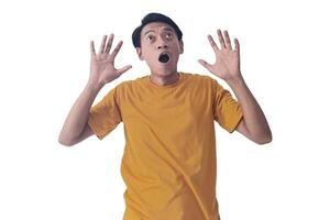 Portrait of an Asian man wearing a orange T-shirt, expressing surprise and shock with open palms, isolated against a white background. photo