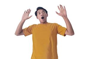 Portrait of an Asian man wearing a orange T-shirt, expressing surprise and shock with open palms, isolated against a white background. photo