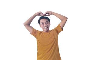 Handsome asian man with smiling in love doing heart symbol shape with hands. romantic concept.Indonesian man with love emoji. young Asian man feels happy and romantic shapes heart gesture expresses. photo