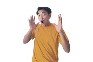 Portrait of an Asian man wearing a orange T-shirt, expressing surprise and shock with open palms, isolated against a white background. photo
