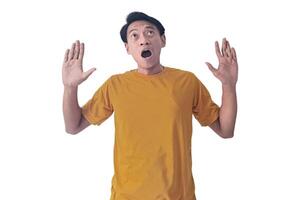 Portrait of an Asian man wearing a orange T-shirt, expressing surprise and shock with open palms, isolated against a white background. photo
