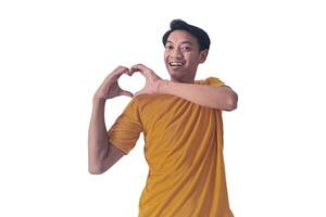 Handsome asian man with smiling in love doing heart symbol shape with hands. romantic concept.Indonesian man with love emoji. young Asian man feels happy and romantic shapes heart gesture expresses. photo