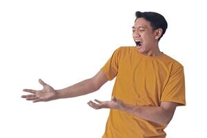 Portrait of an Asian man wearing a orange T-shirt, expressing surprise and shock with open palms, isolated against a white background. photo
