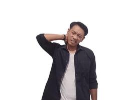A man in a black shirt holds his neck with a pained expression, indicating discomfort or neck pain. The plain white background emphasizes his distress and highlights photo