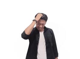 A man in a black shirt holds his head with a pained expression, indicating a headache or discomfort. The plain white background emphasizes his distress and highlights his posture and expression. photo