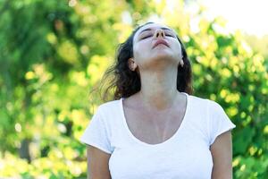 Young woman sweating on a hot summer day taking a deep breath while looking at the sky photo