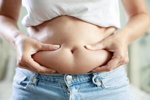 Young woman touching her belly looking in mirror at home photo