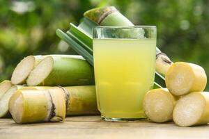 Drink from sugar cane juice, squeezed sugar cane juice with sugar cane stalks and natural background photo