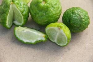Bergamot fruits or sliced kaffir lime or Citrus hystrix on wooden table and natural green background photo