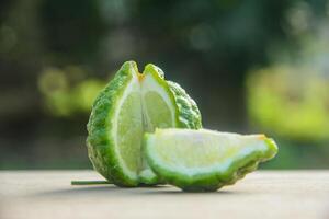 Bergamot fruits or sliced kaffir lime or Citrus hystrix on wooden table and natural green background photo