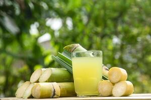 Drink from sugar cane juice, squeezed sugar cane juice with sugar cane stalks and natural background photo