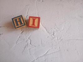 A photo of a wooden block with the words hi written on it, styled in isolation with space for text.