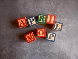 A photo of a wooden block with the words April Mop written on it, styled in isolation with space for text.