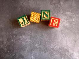 A photo of a wooden block with the words june written on it, styled in isolation with space for text.