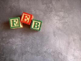 A photo of a wooden block with the words february written on it, styled in isolation with space for text.
