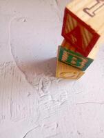 A photo of a wooden block with the words ABC alphabet written on it, styled in isolation with space for text.