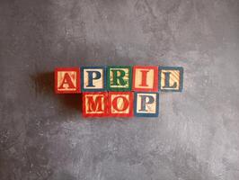 A photo of a wooden block with the words April Mop written on it, styled in isolation with space for text.