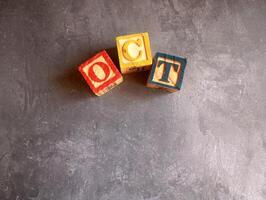 A photo of a wooden block with the words october written on it, styled in isolation with space for text.