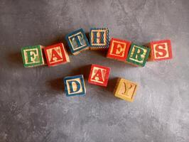 A photo of a wooden block with the words fathers day written on it, styled in isolation with space for text.