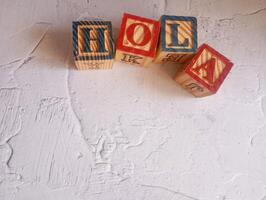 A photo of a wooden block with the words hola written on it, styled in isolation with space for text.