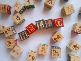 A photo of a wooden block with the words hello written on it, styled in isolation with space for text.