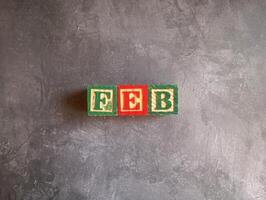 A photo of a wooden block with the words february written on it, styled in isolation with space for text.