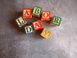 A photo of a wooden block with the words labor day written on it, styled in isolation with space for text.