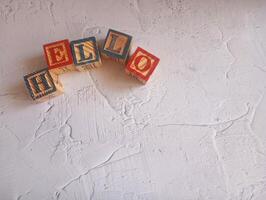 A photo of a wooden block with the words hello written on it, styled in isolation with space for text.