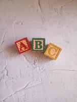 A photo of a wooden block with the words ABC alphabet written on it, styled in isolation with space for text.