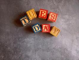 A photo of a wooden block with the words tuesday written on it, styled in isolation with space for text.