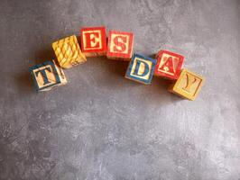 A photo of a wooden block with the words tuesday written on it, styled in isolation with space for text.