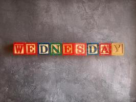 A photo of a wooden block with the words wednesday written on it, styled in isolation with space for text.