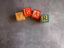 A photo of a wooden block with the words year written on it, styled in isolation with space for text.