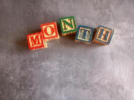 A photo of a wooden block with the words month written on it, styled in isolation with space for text.